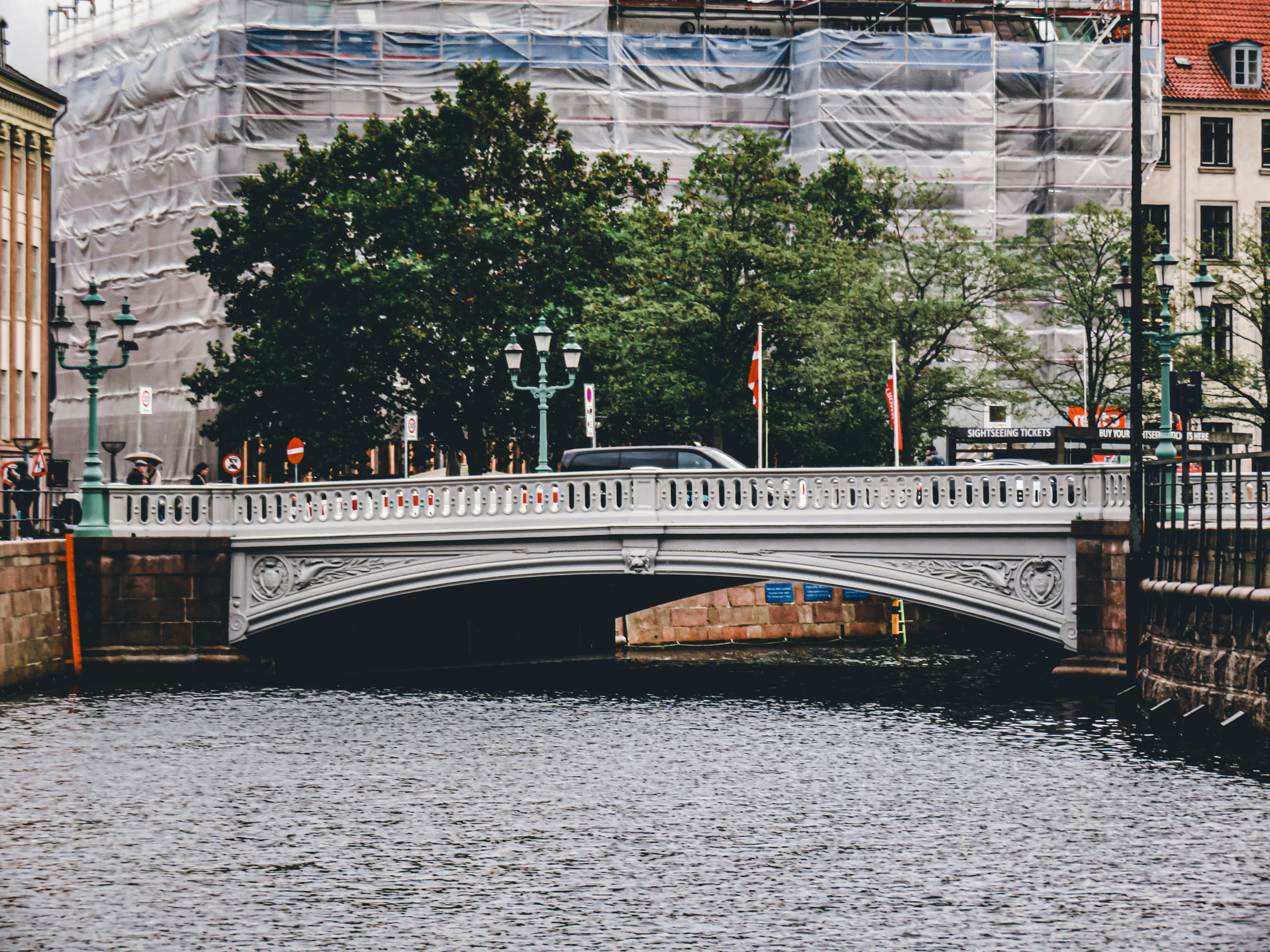 A bridge spans a river with buildings behind.