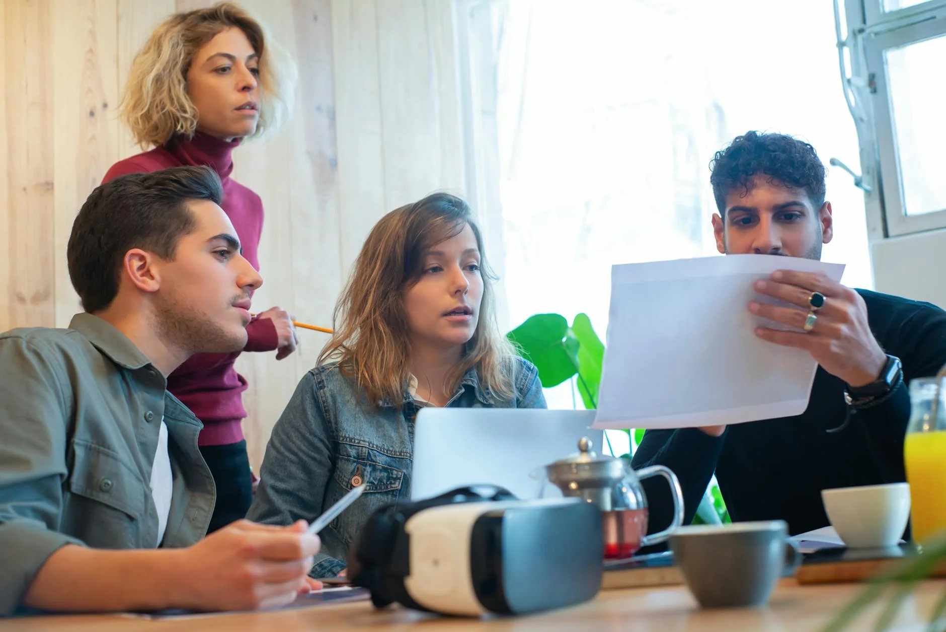 Four colleagues engaged in a productive discussion in a well-lit office environment, showcasing teamwork and diversity.