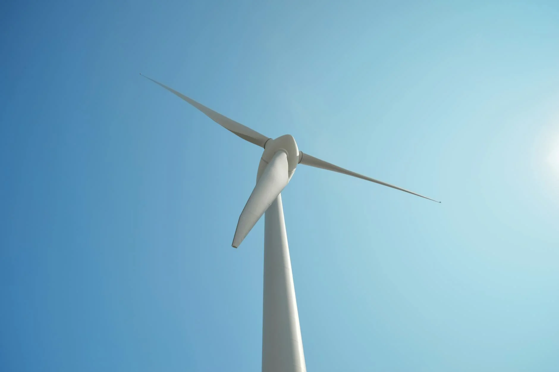 A modern wind turbine captured in Liepāja, Latvia, against a clear blue sky symbolizing clean energy.