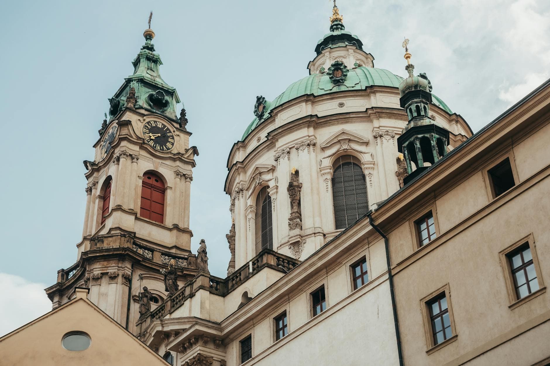 Close-up of Baroque architecture featuring the dome and clock tower of St. Nicholas Church in Prague.