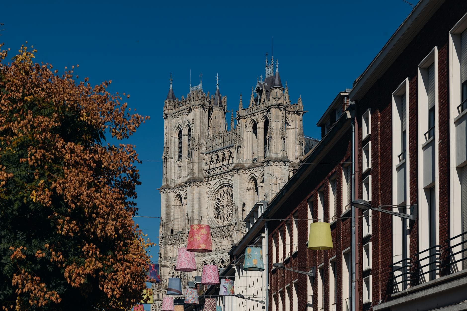 View of Amiens Cathedral with colorful street decorations on a sunny day.