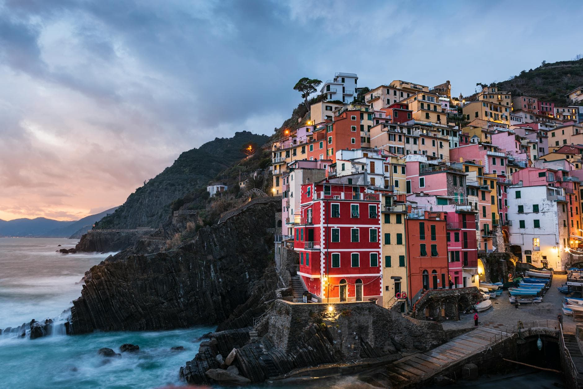 Scenic view of Riomaggiore's vibrant houses on a cliffside at sunset, Liguria, Italy.