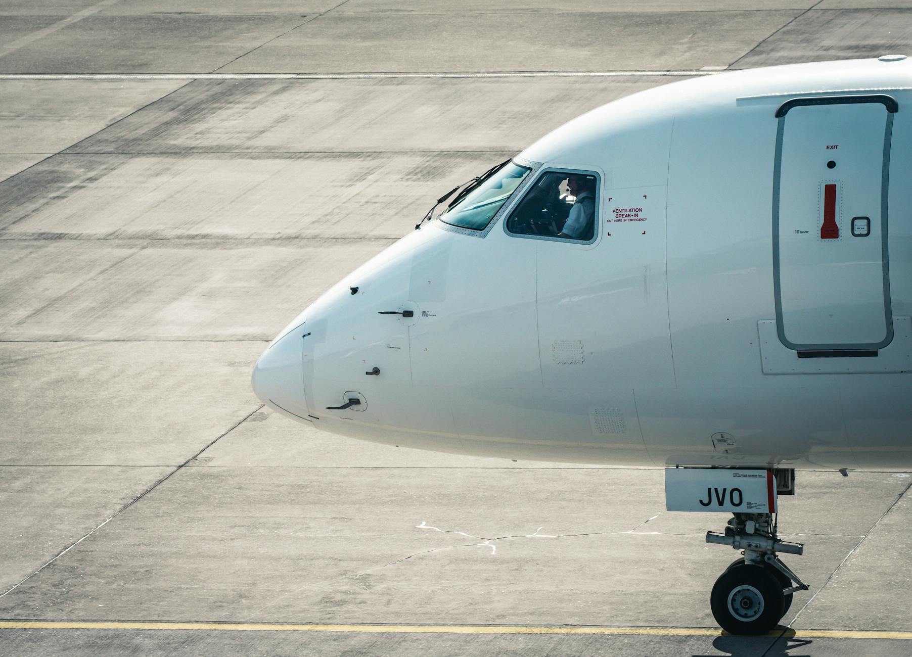 Close-up of an airplane on the tarmac at Zurich Airport with a pilot visible in the cockpit.