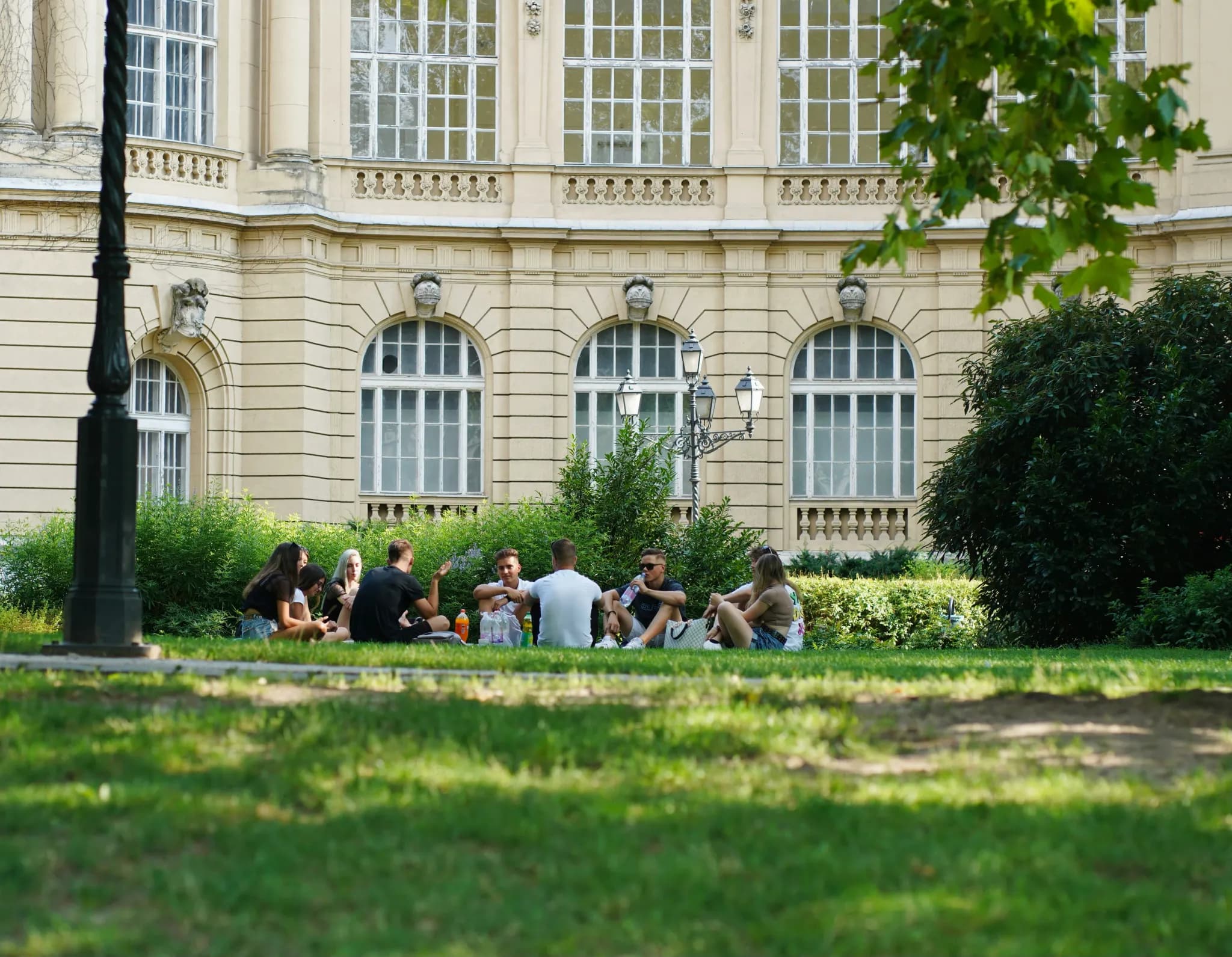 people sitting on green grass field near white concrete building during daytime