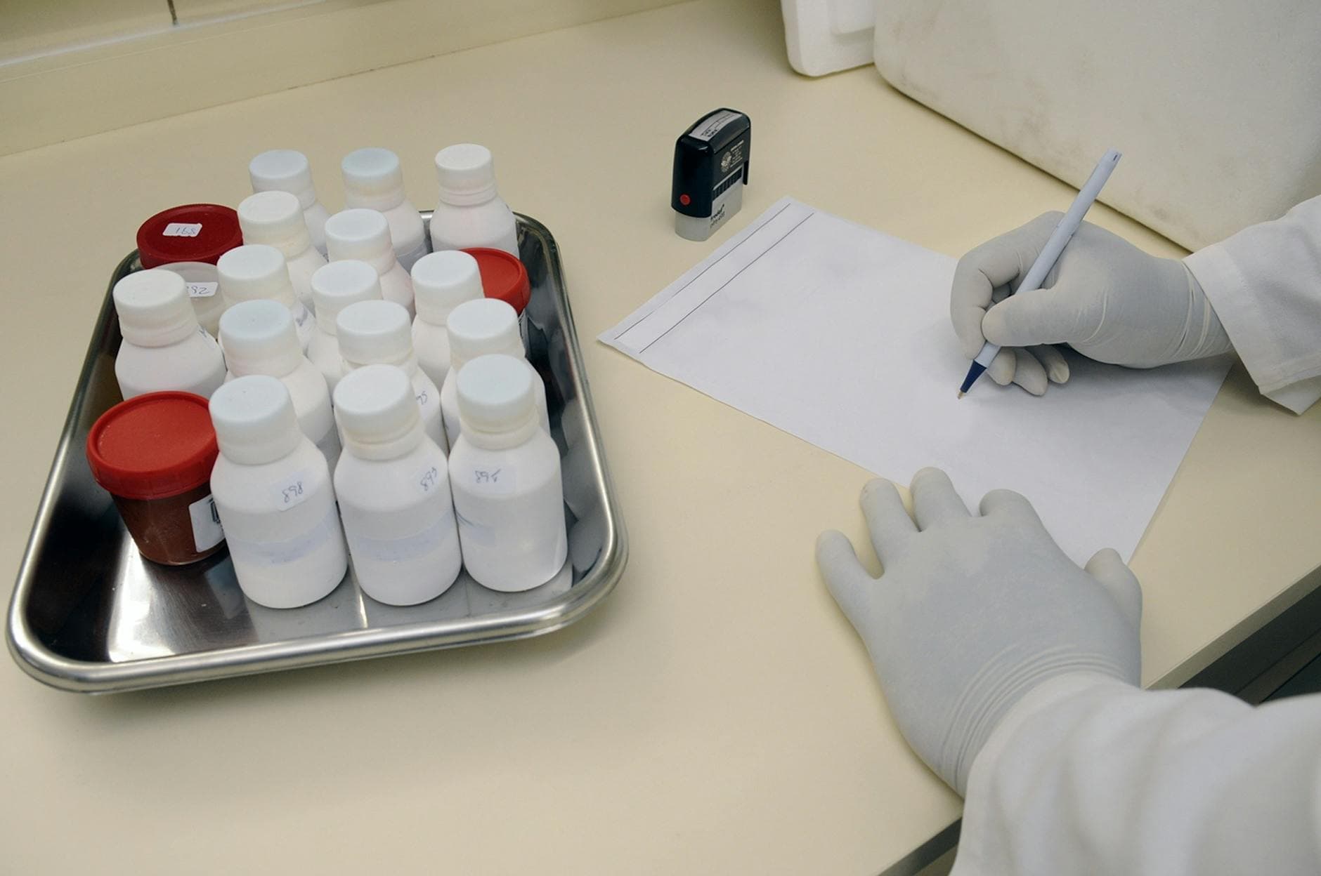 Laboratory technician writing report with samples in a medical lab.