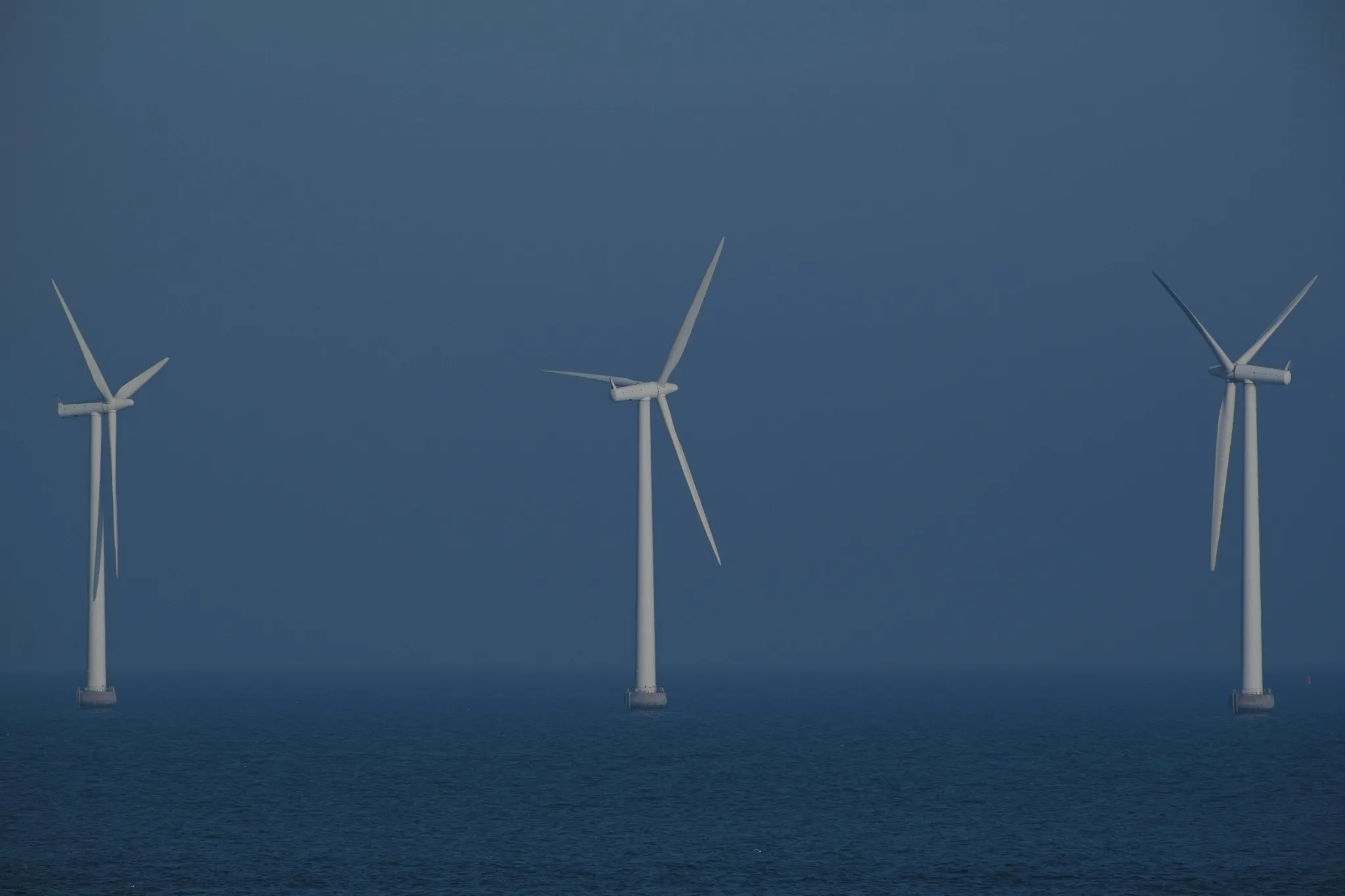 Wind turbines stand in the ocean, generating clean energy.