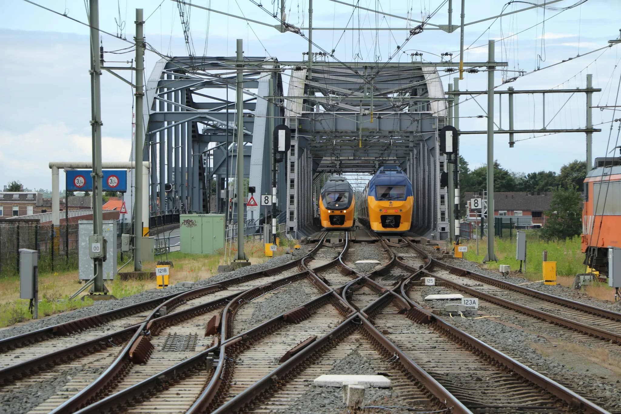 Two yellow trains approaching a bridge crossing