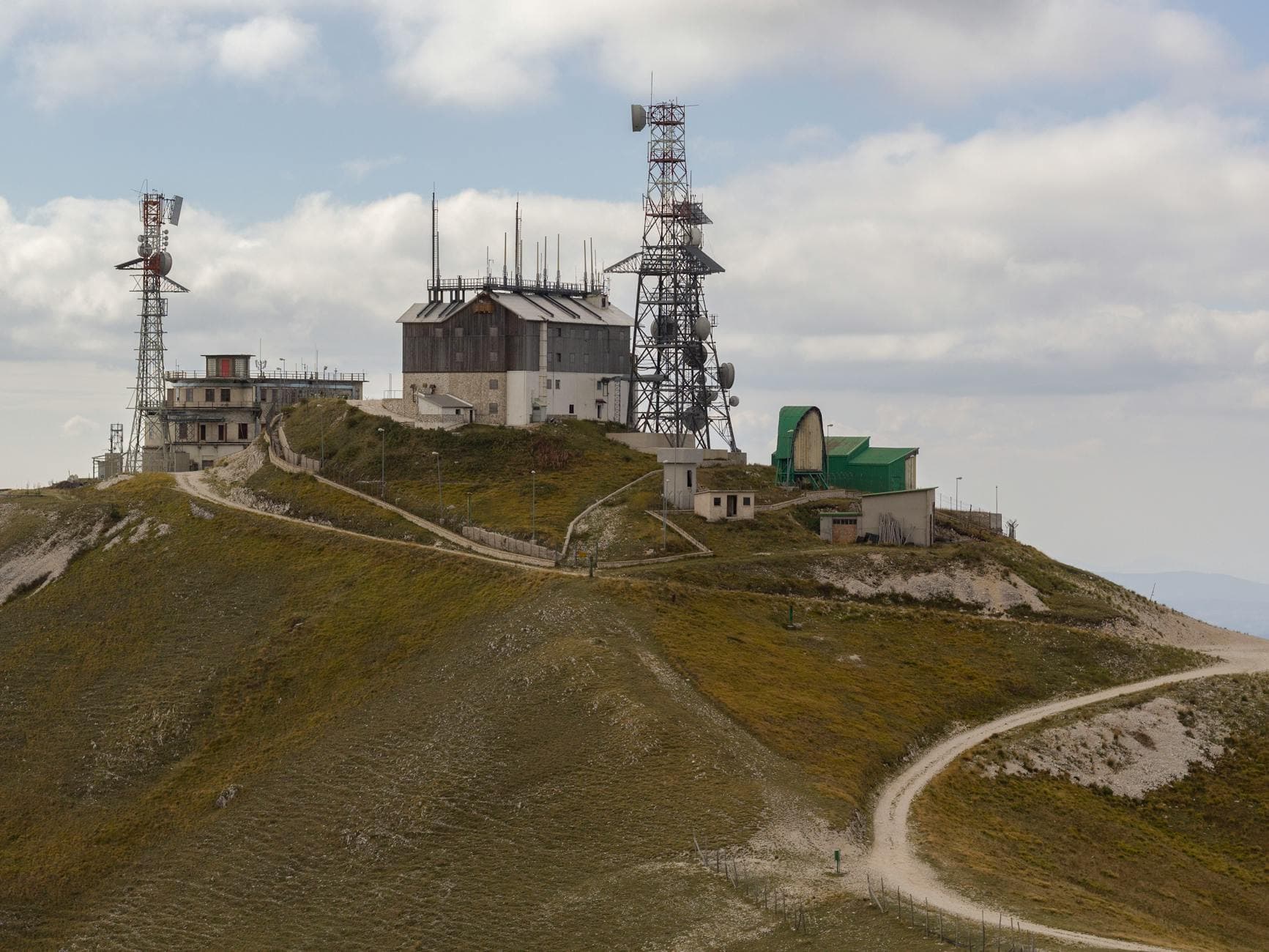 Remote hilltop in Lazio with communication towers and scenic views under a cloudy sky.