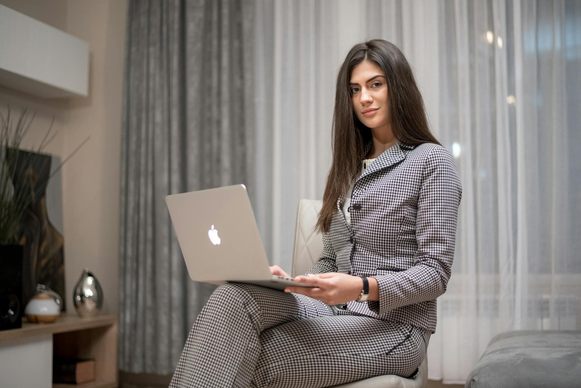 Confident woman using a laptop at home for remote work in a stylish living room.