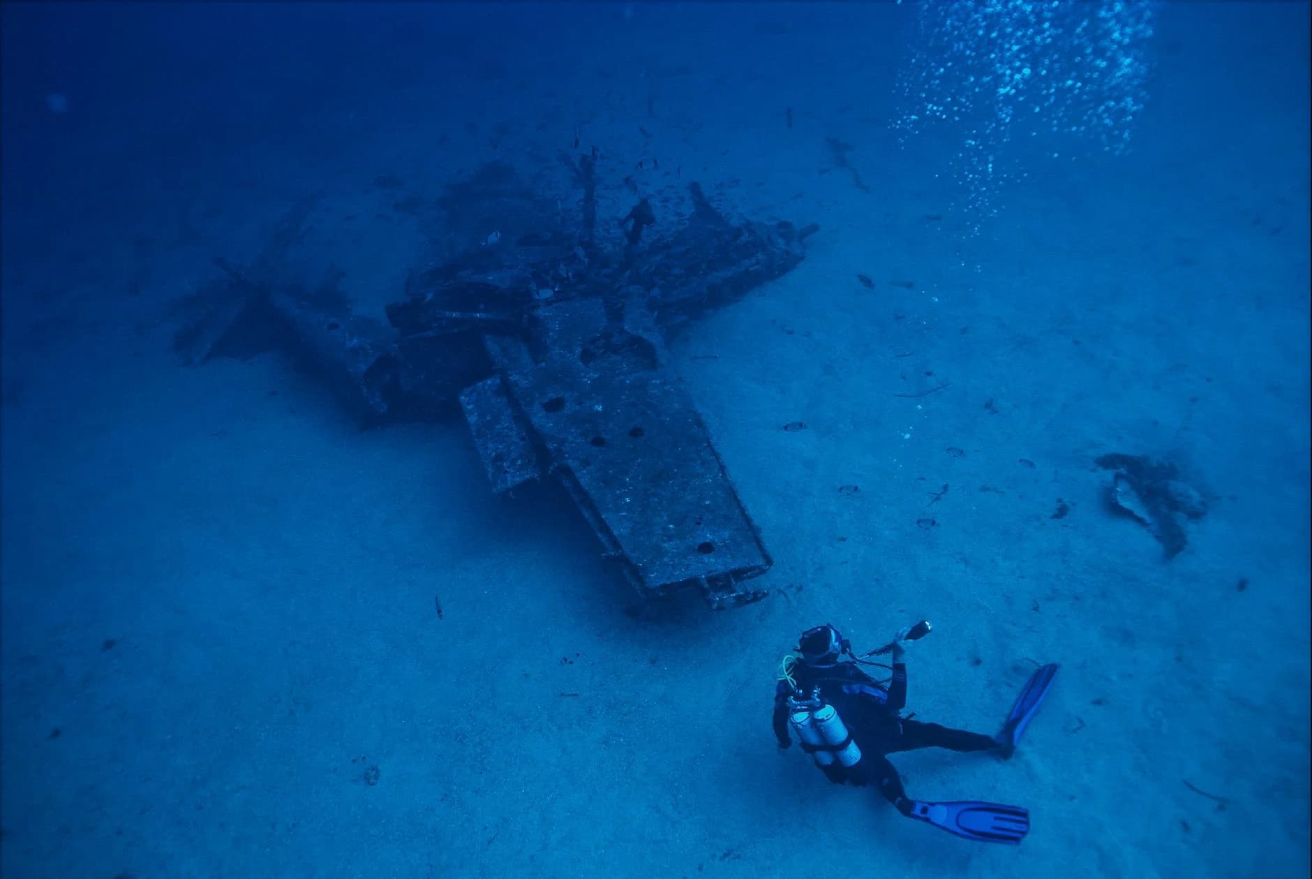 A scuba diver explores a submerged shipwreck deep underwater, capturing adventure and exploration.