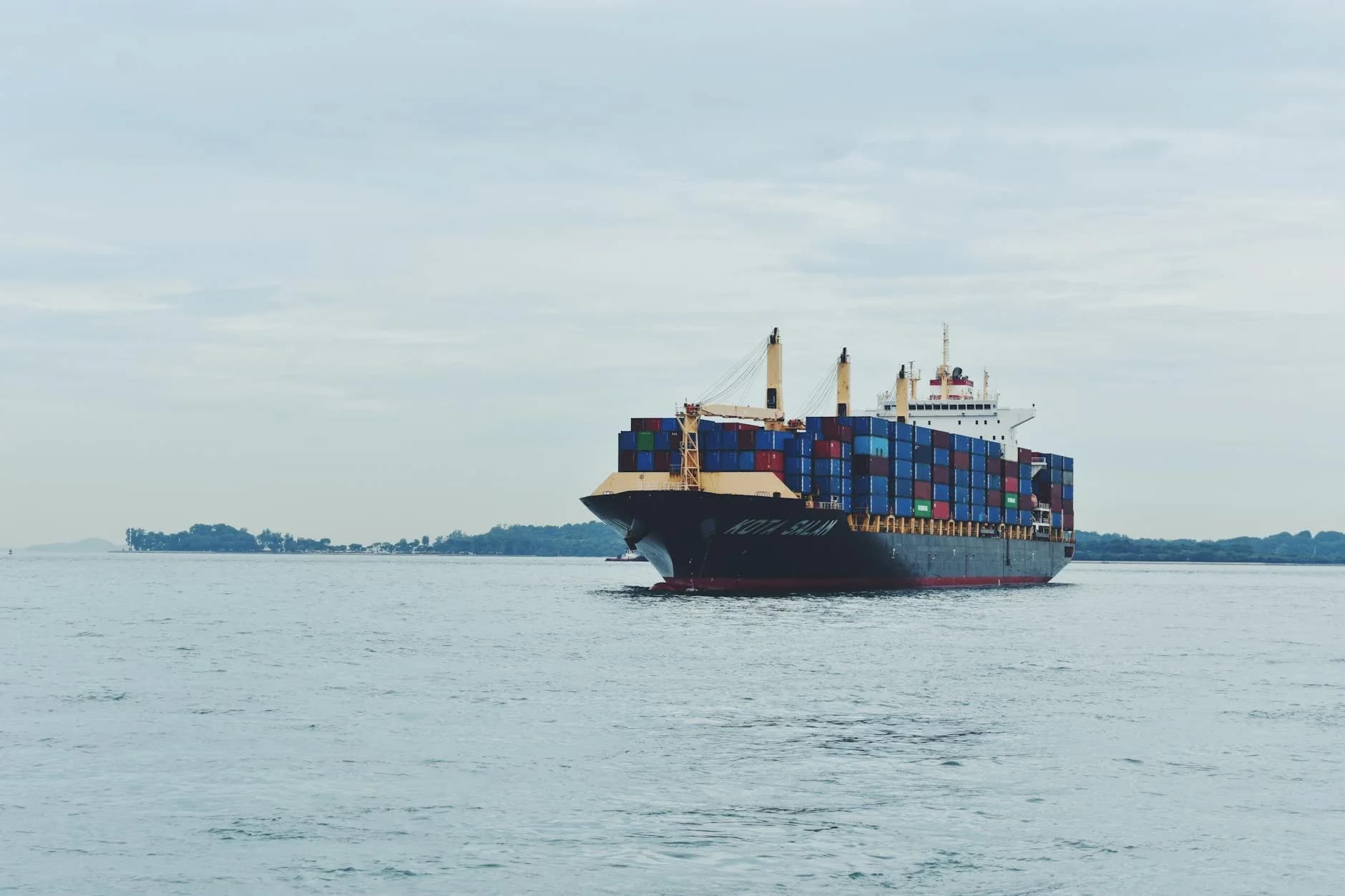 Large cargo ship transporting containers across a calm sea, symbolizing global logistics.