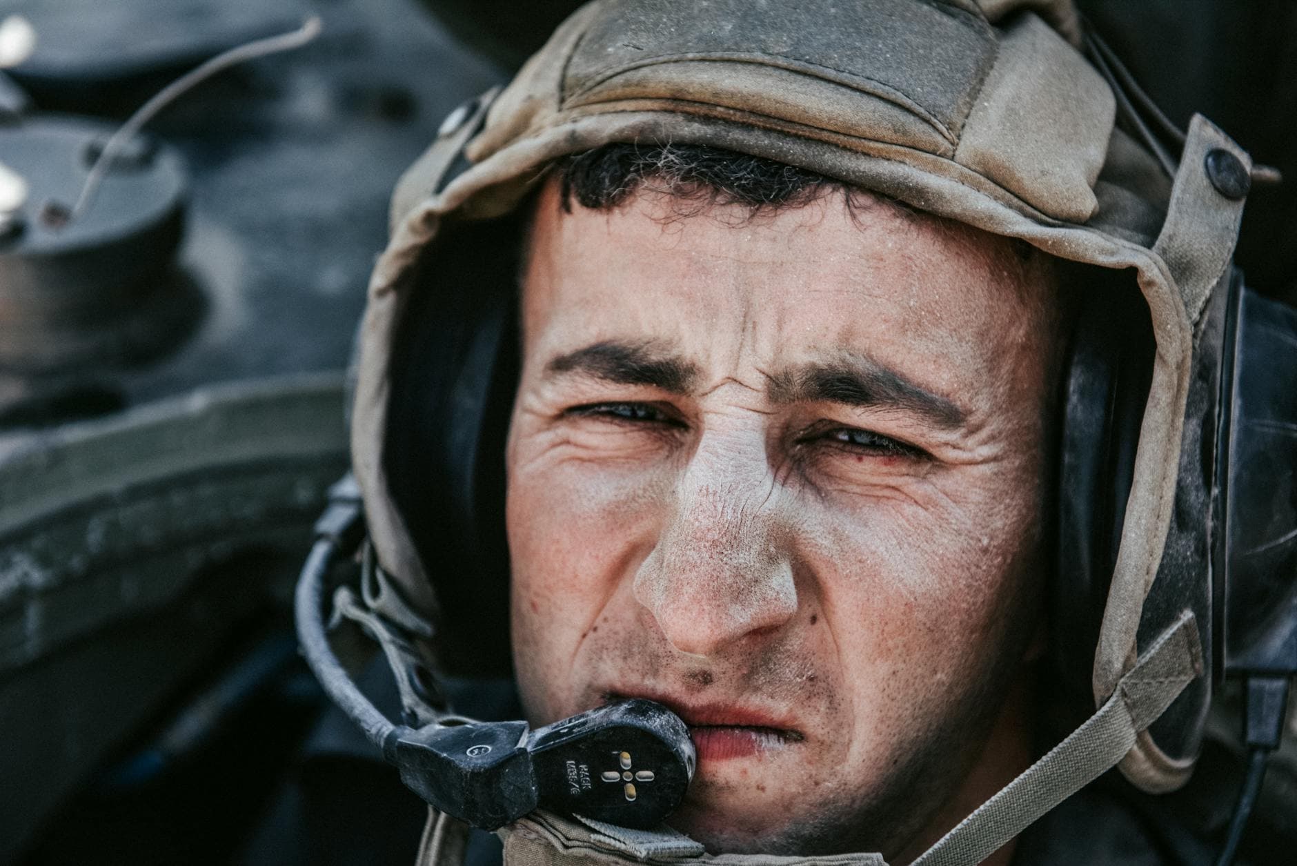 Intense close-up of a soldier wearing a military helmet and communication headset, focused and serious.