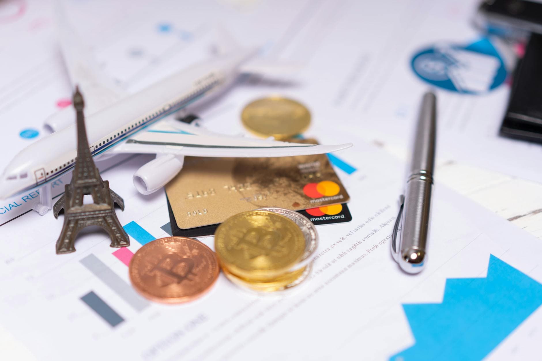 A travel finance concept featuring cryptocurrency, credit card, airplane model, and Eiffel Tower on financial documents.