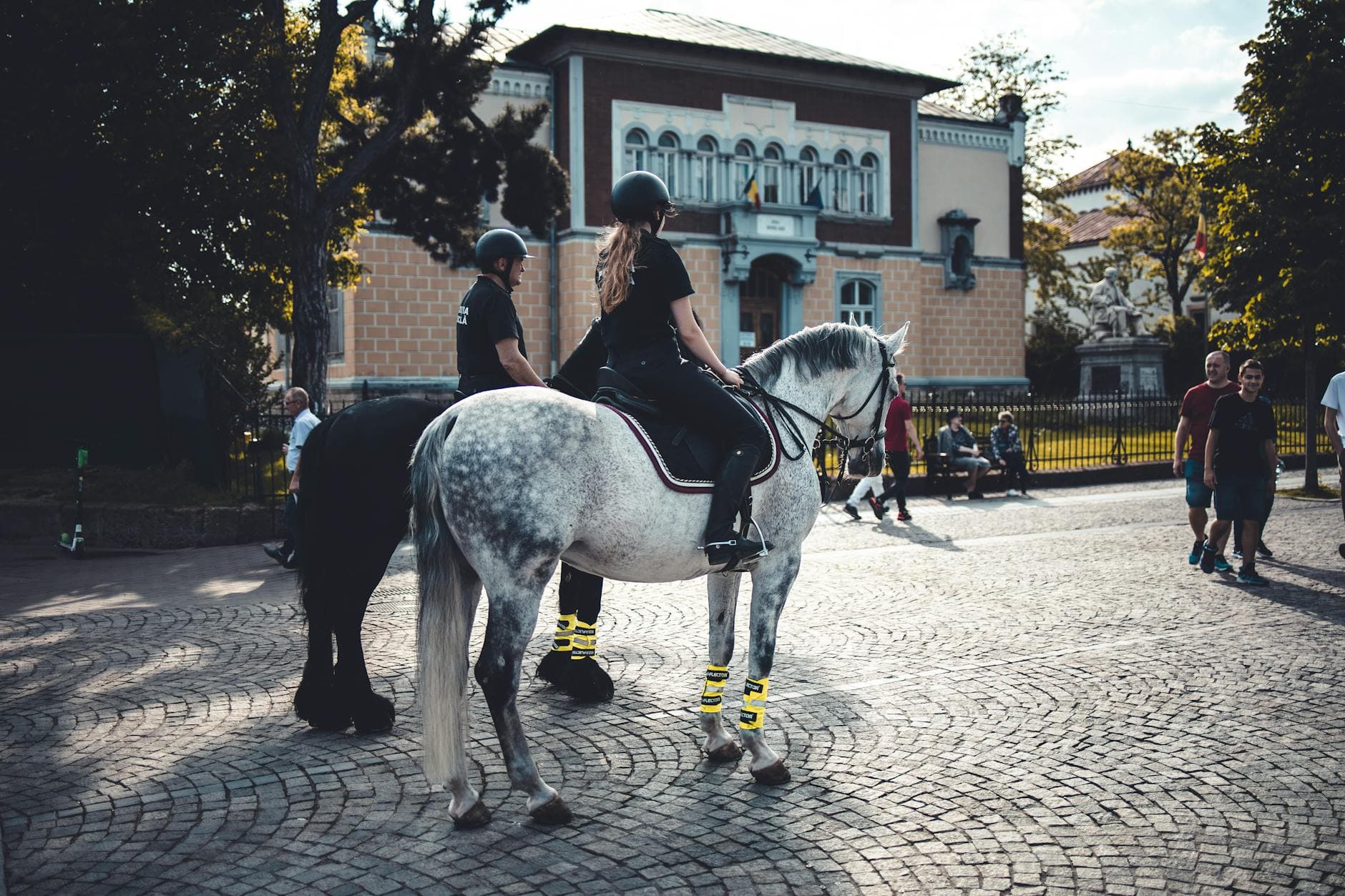 Mounted police officers patrolling a cobblestone square in Iași, Romania, on a sunny day.