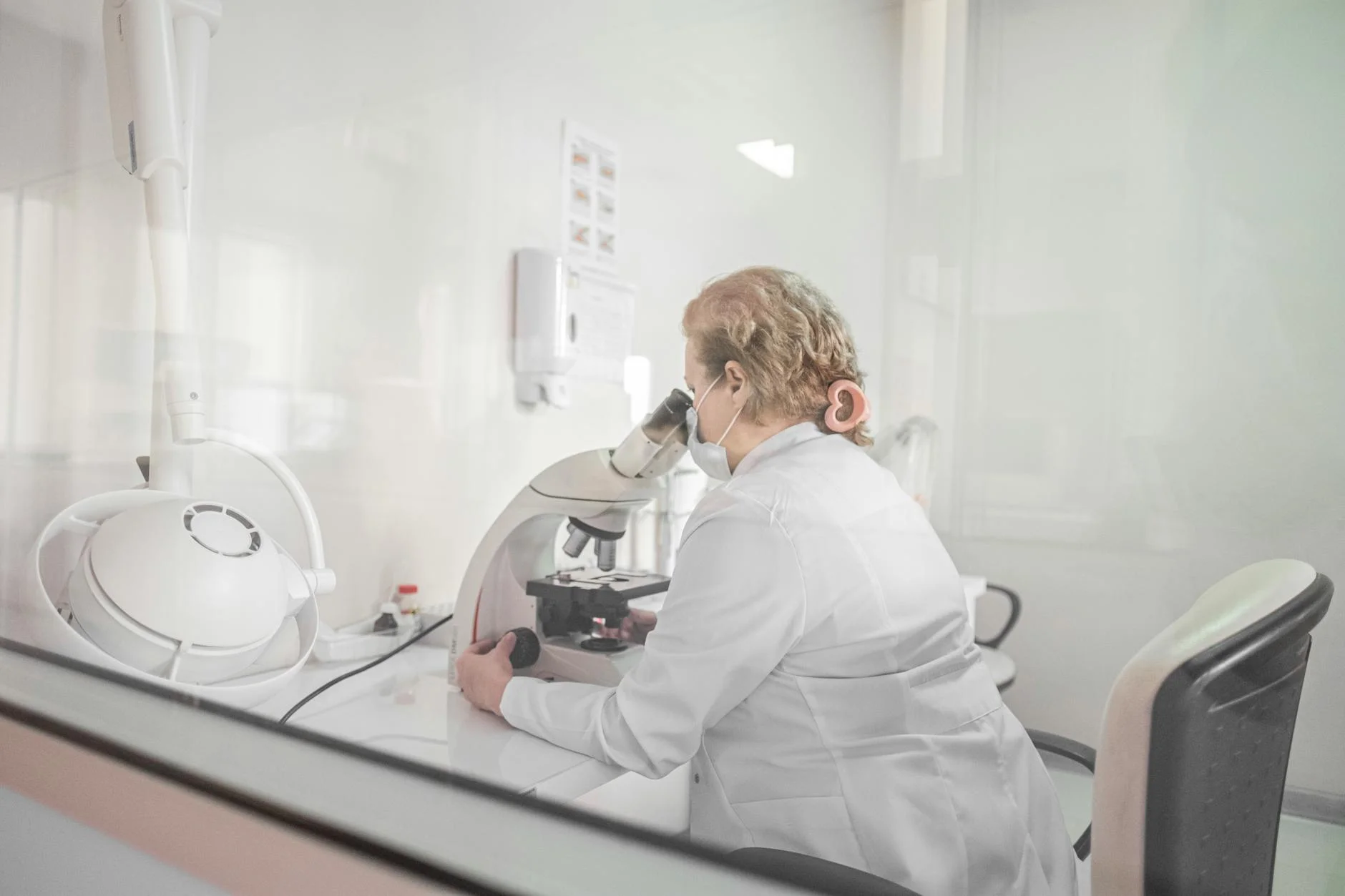 A scientist works with a microscope in a bright, modern lab setting, wearing a lab coat.
