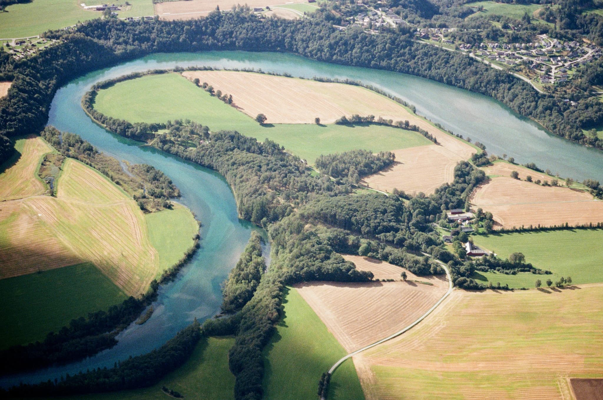 Curving river through green fields and trees