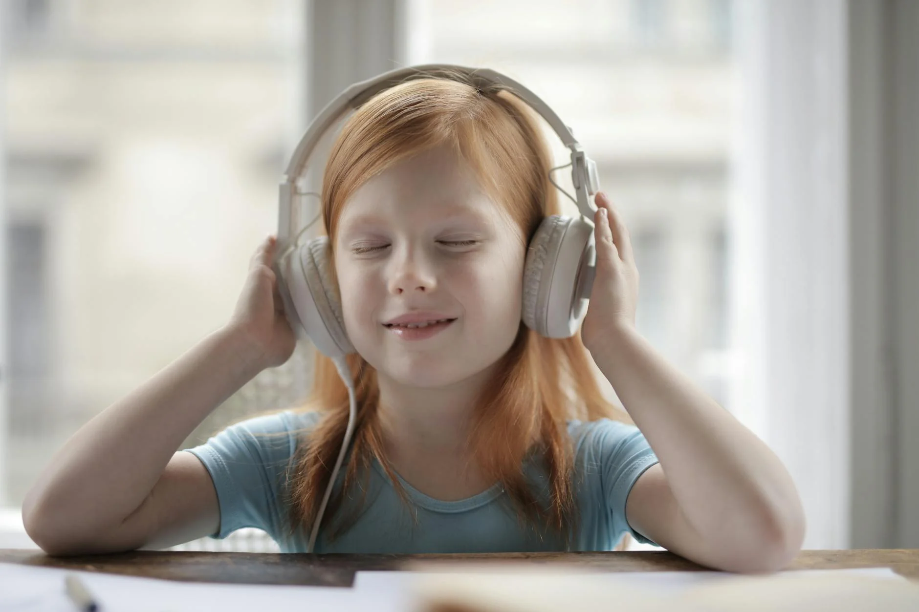 Smiling girl enjoying music with headphones indoors. Happy and content.
