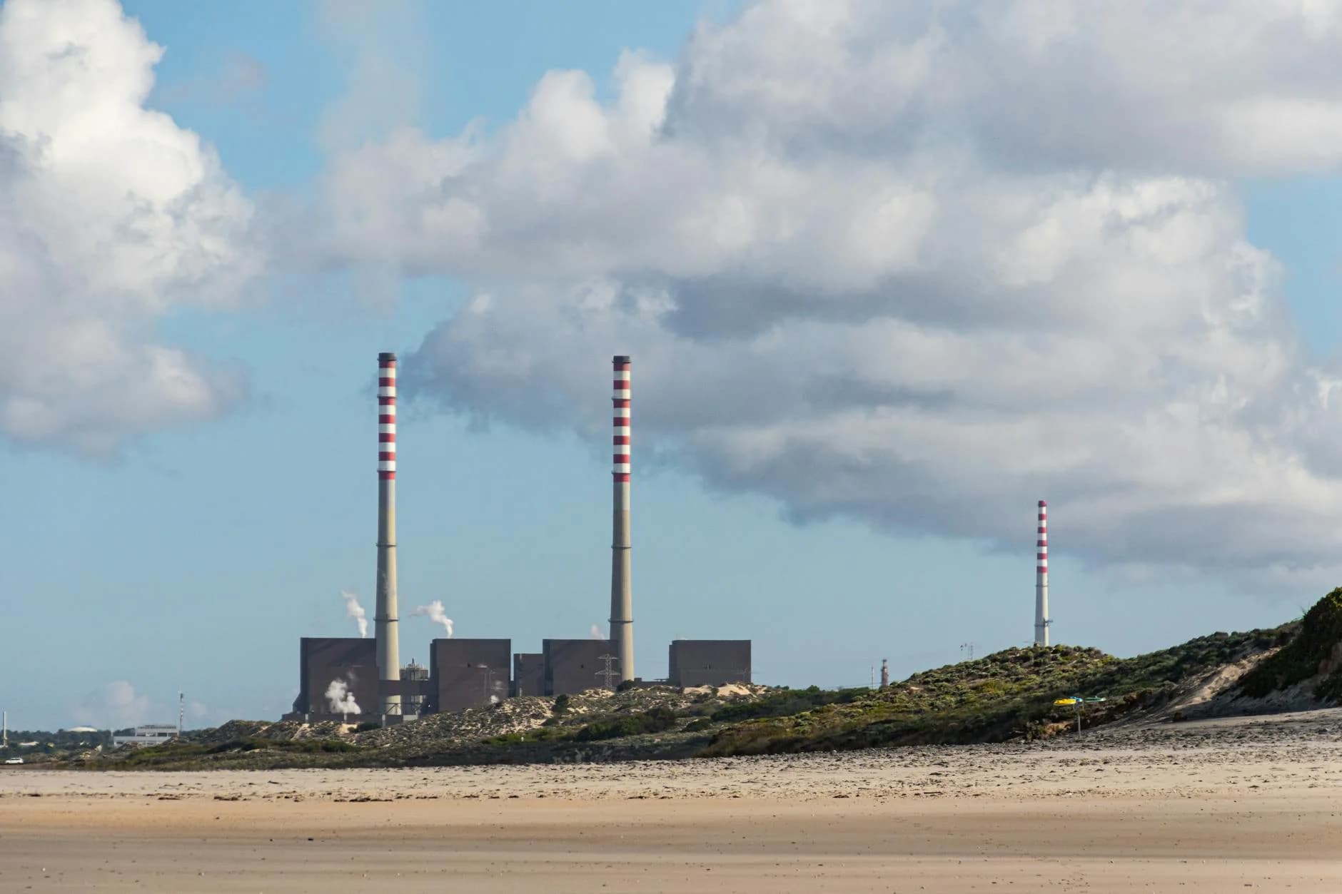 Cloudy day at a beach in Portugal featuring factory smokestacks.