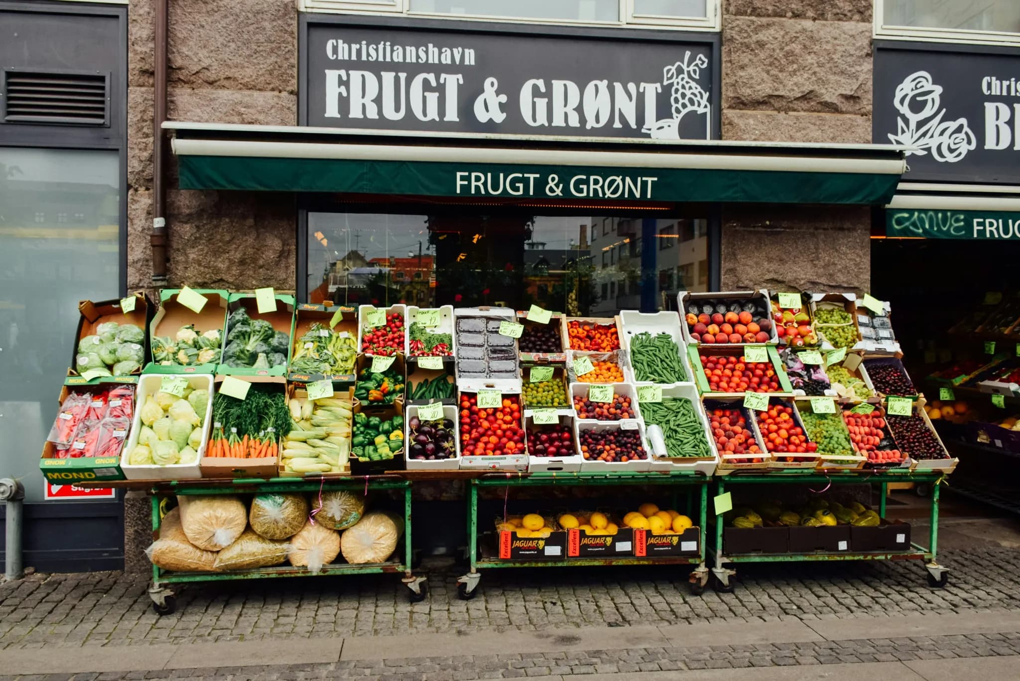 a fruit and vegetable stand in front of a store