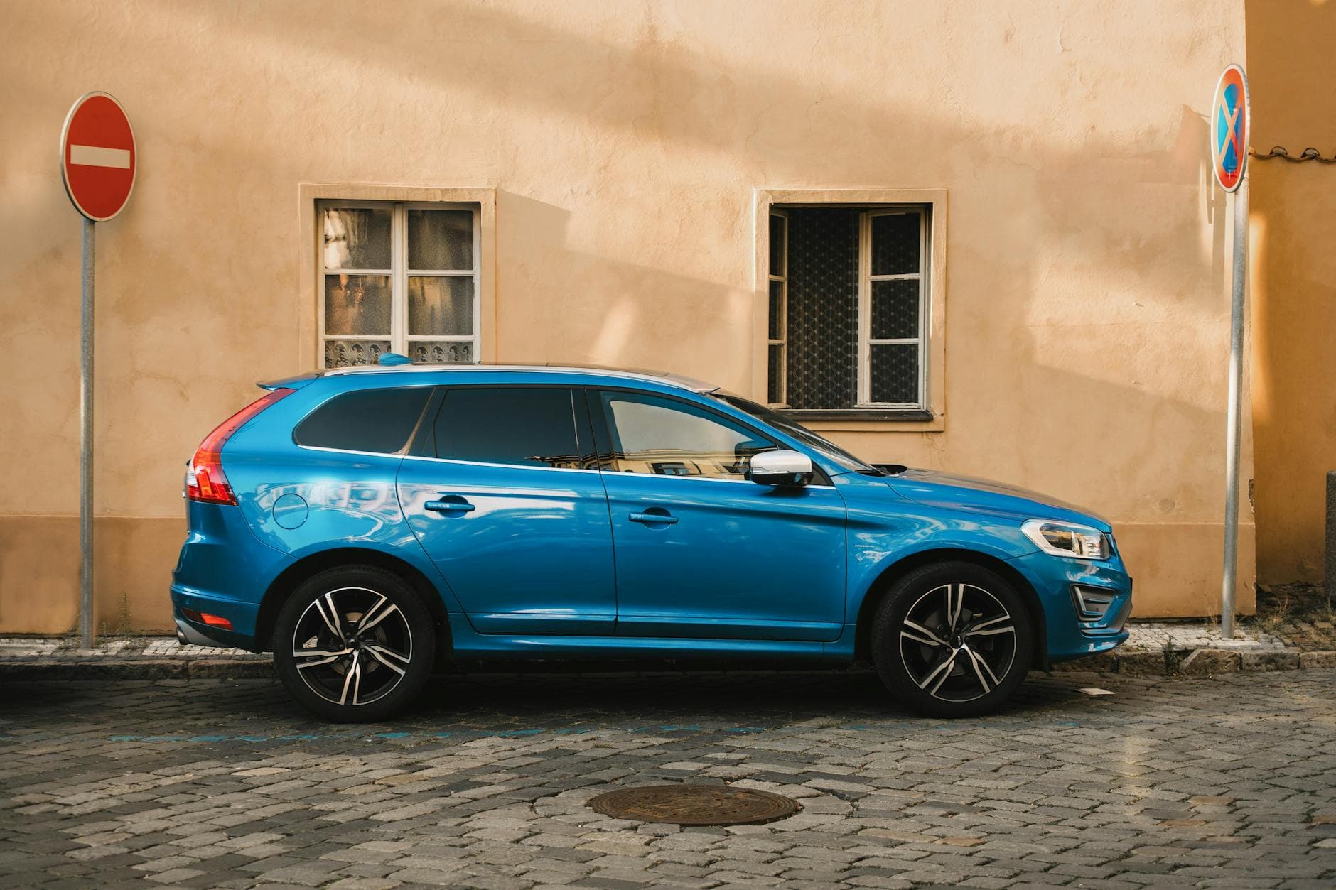 Blue SUV parked by a historic building in Prague, showcasing street signs and city vibes.