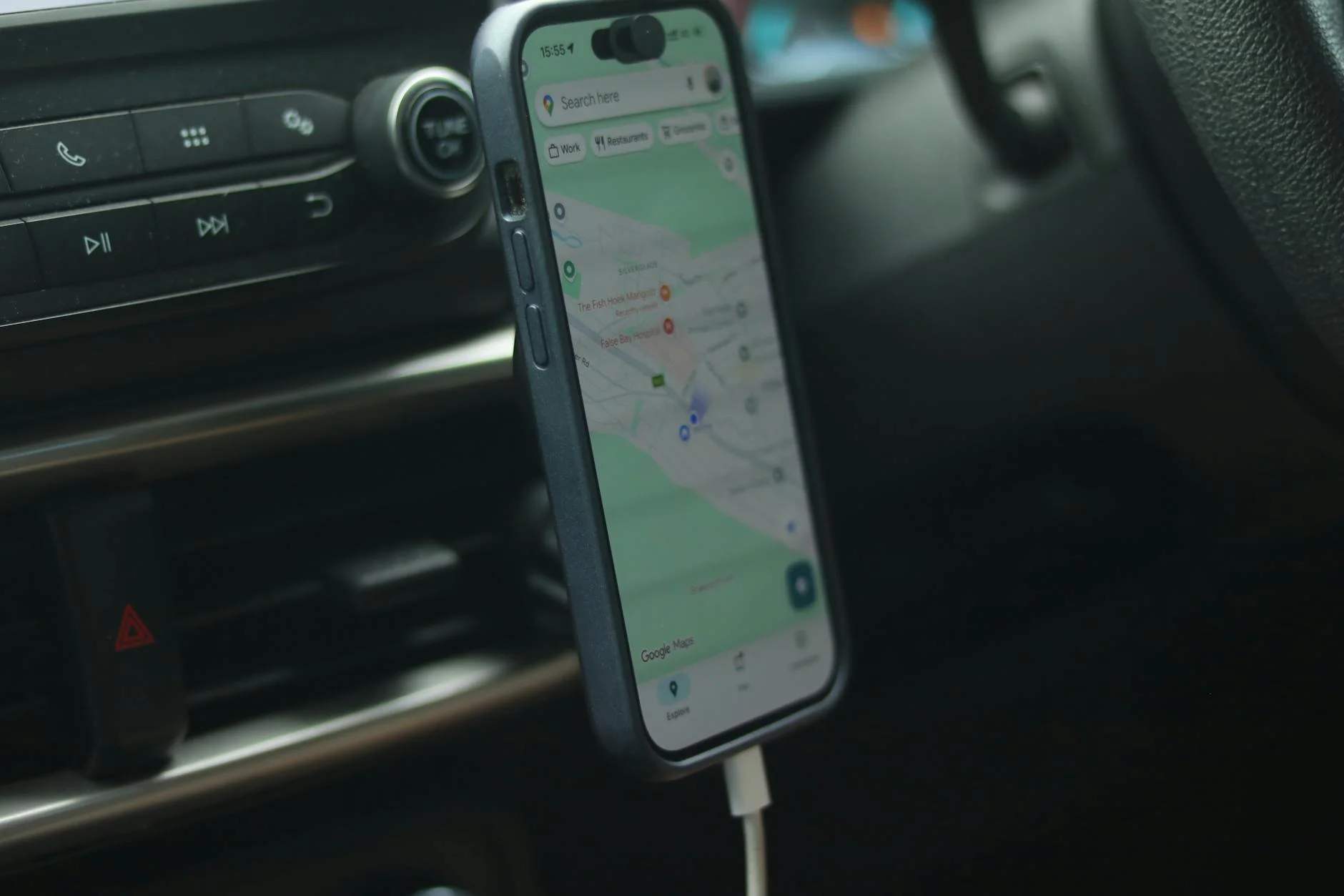 A smartphone with a map app displayed inside a car, showing modern navigation.