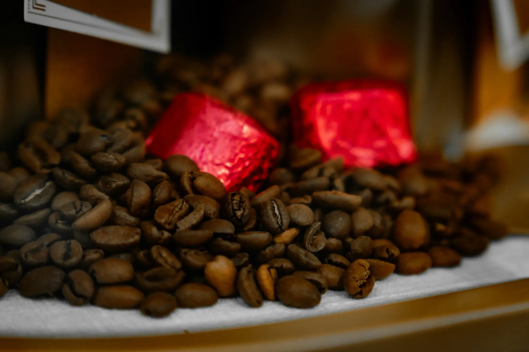 Two red candies nestled in roasted coffee beans.