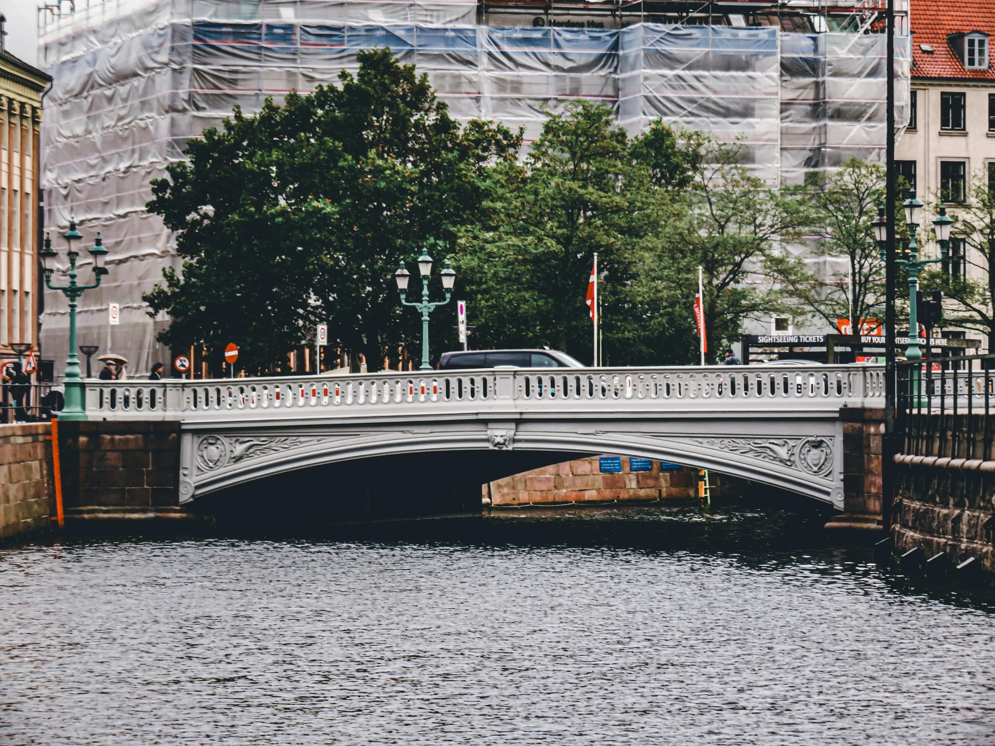 A bridge spans a river with buildings behind.