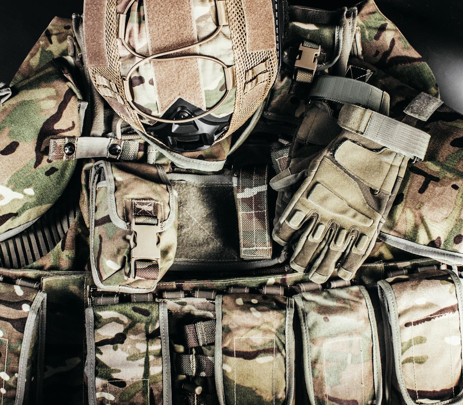 Close-up of tactical military gear with camouflage helmet and gloves showcasing readiness.