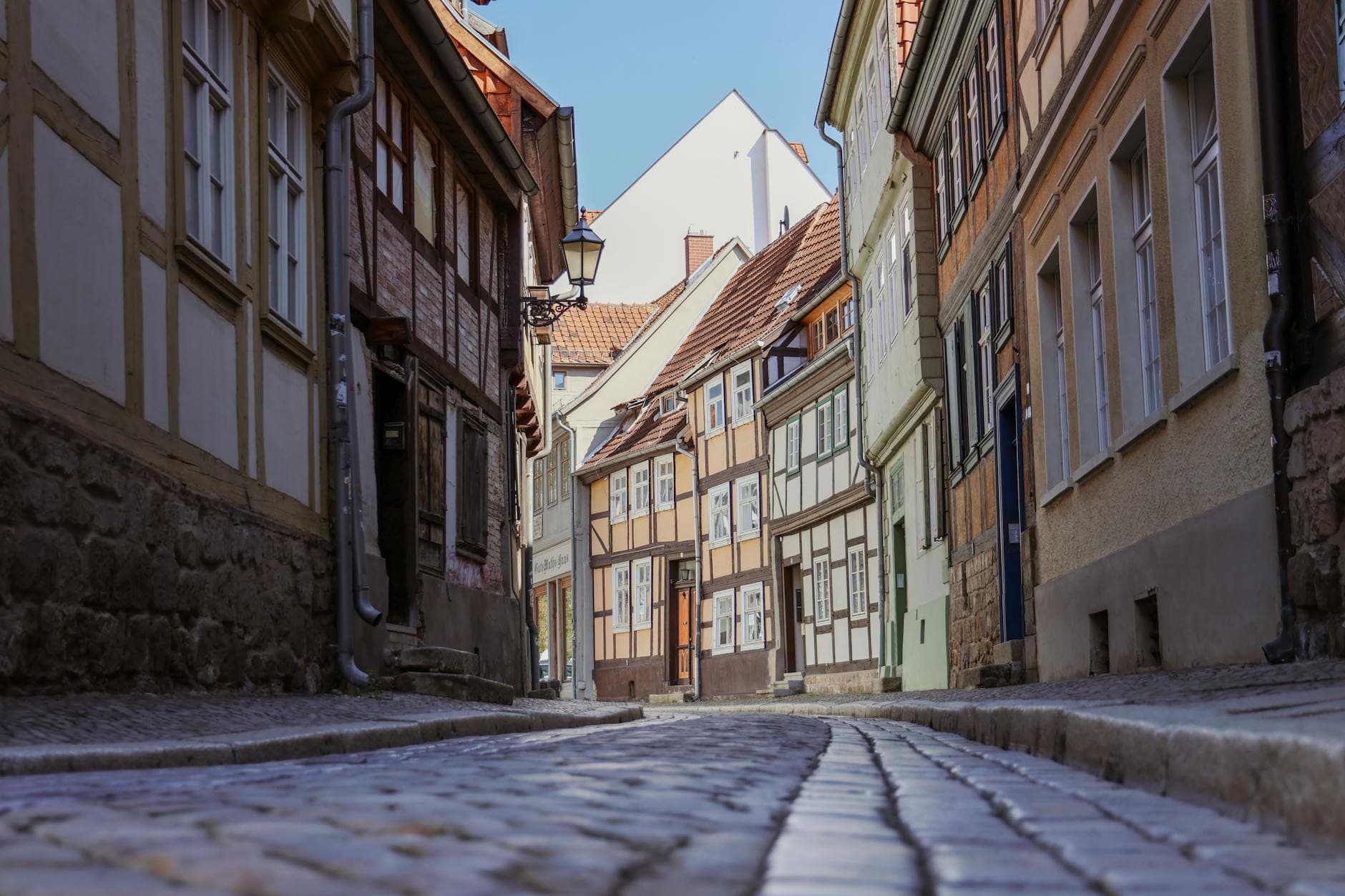 A picturesque cobblestone street with historic half-timbered houses in Quedlinburg, Germany.