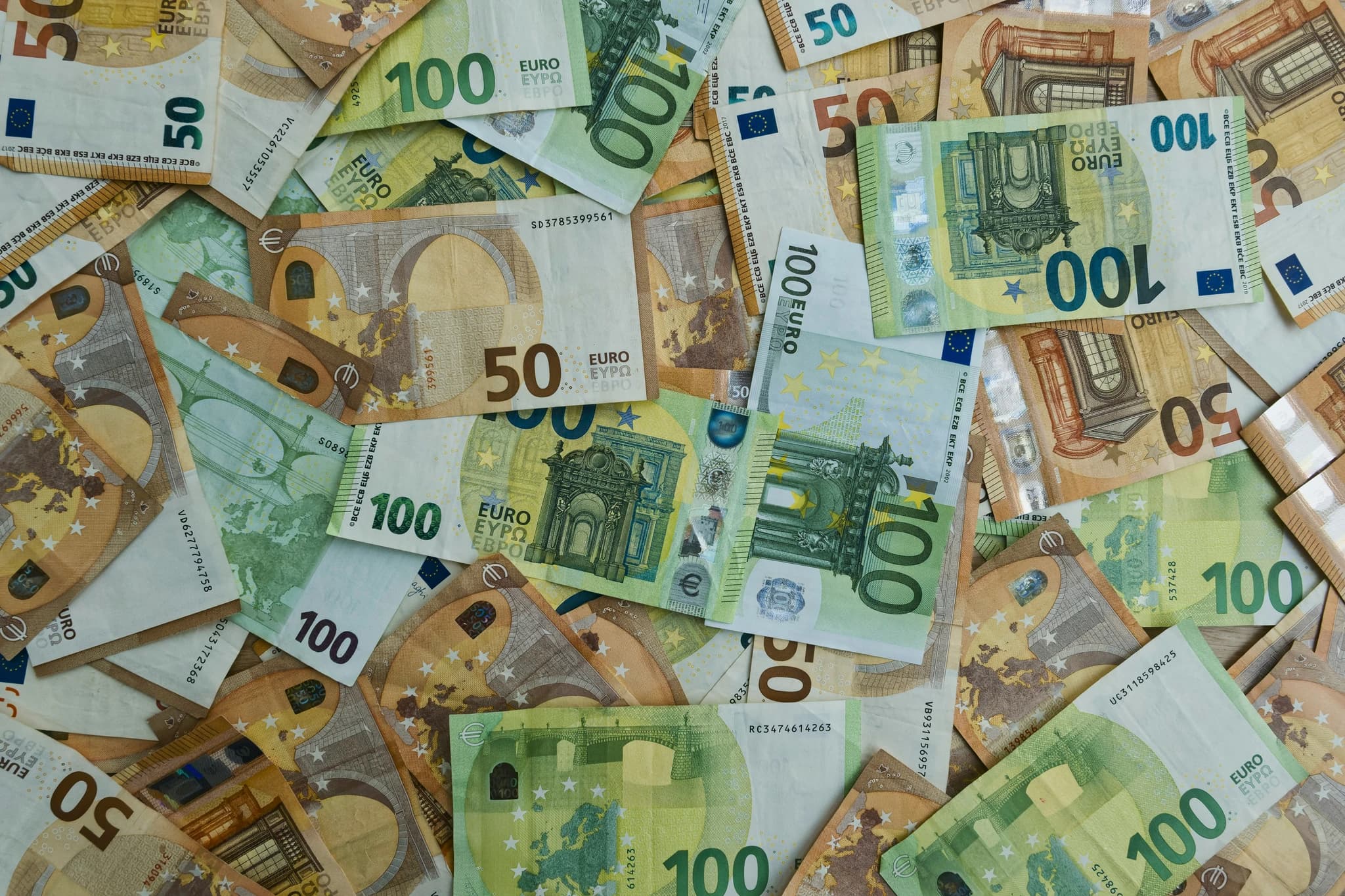 Scattered euro banknotes of 50 and 100 denominations.
