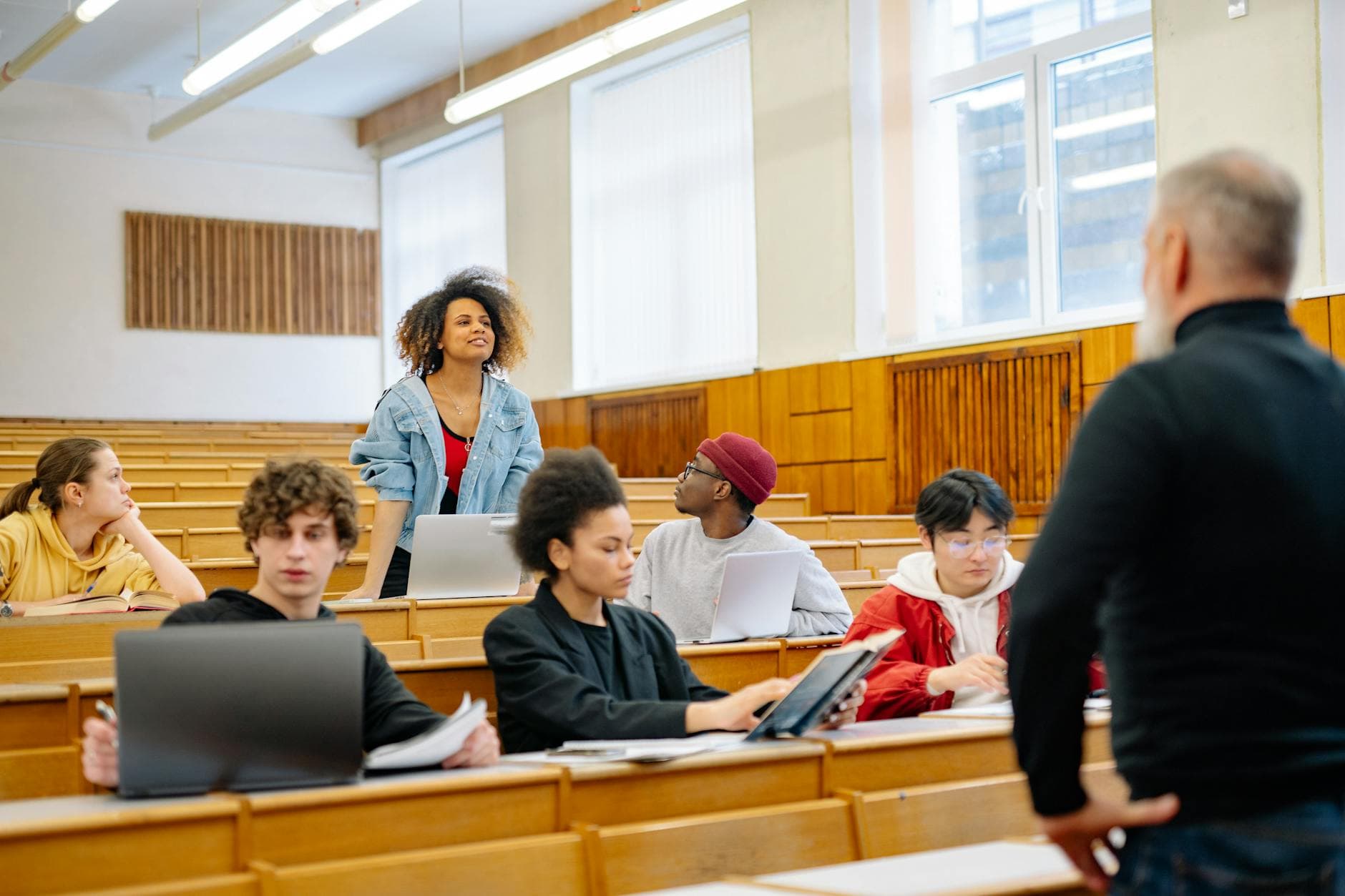 A diverse group of university students actively participating in a lecture, engaging with the professor.