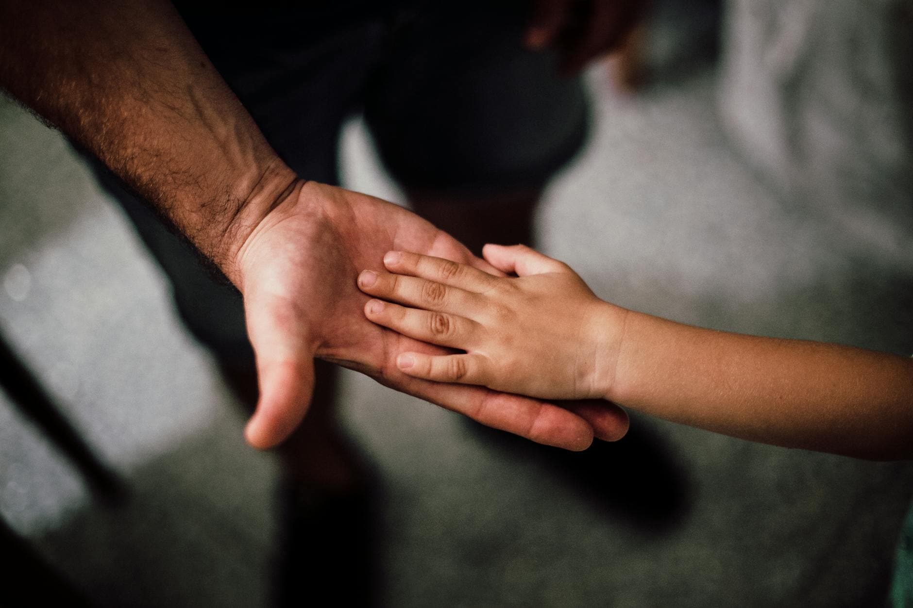 Close-up of a child's hand resting gently on a man's hand, symbolizing love and support.