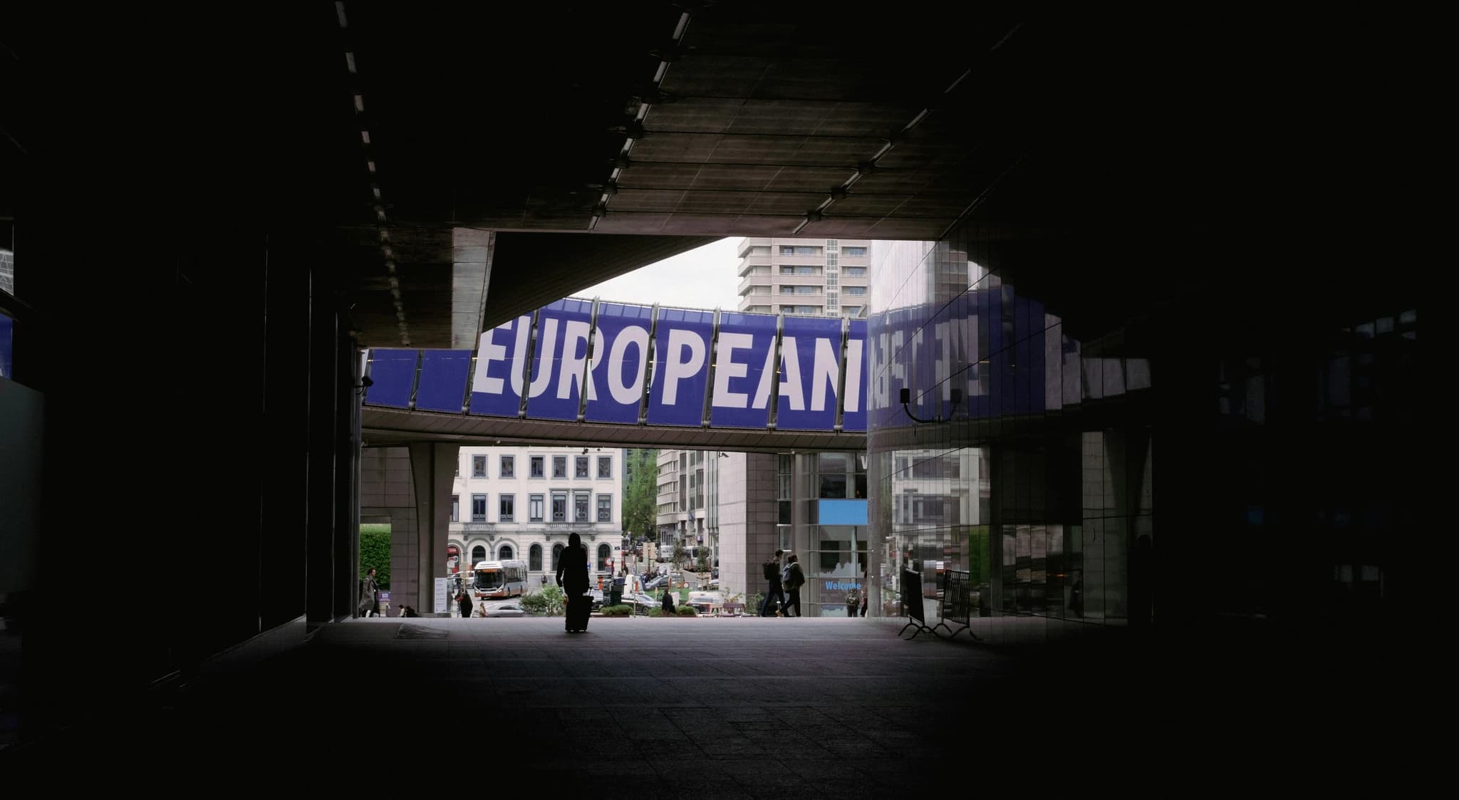 a person walking under a bridge with a european sign above it