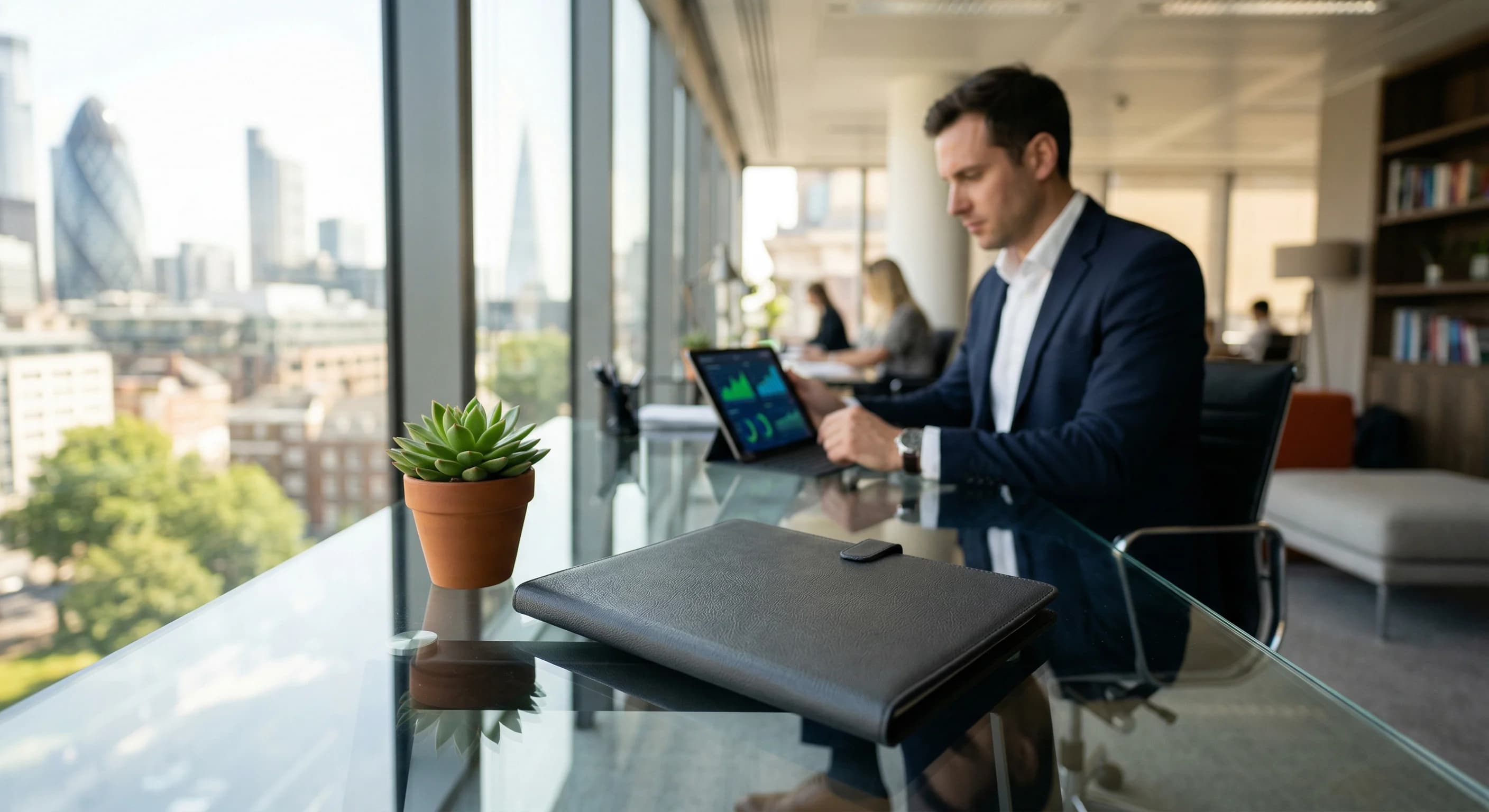 A close-up photorealistic shot of a modern glass desk in a bright, sunlit European corporate office. On the desk rests an elegant, unmarked document folder alongside a small vibrant green potted plant